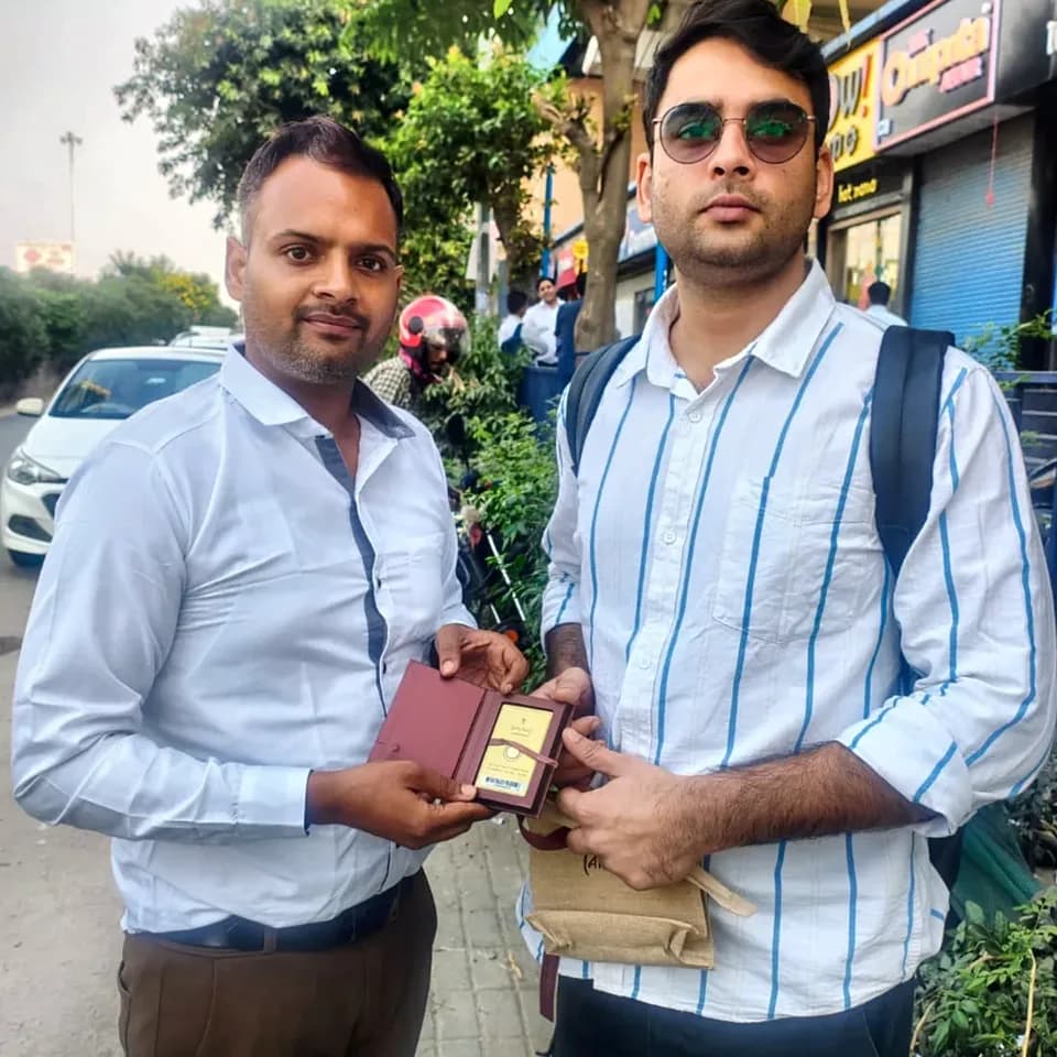 A ProperPaisa advisor handing a Tanishq gold coin to a customer after their loan was disbursed