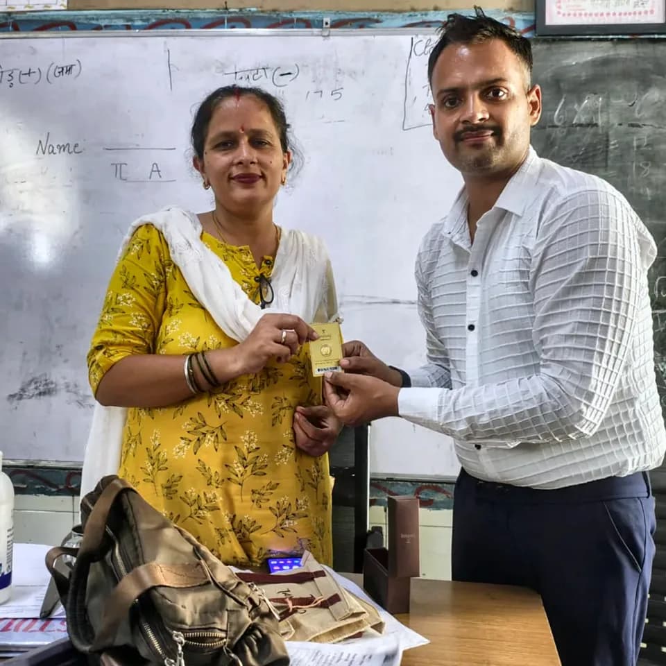A ProperPaisa advisor handing a Tanishq gold coin to a customer after their loan was disbursed