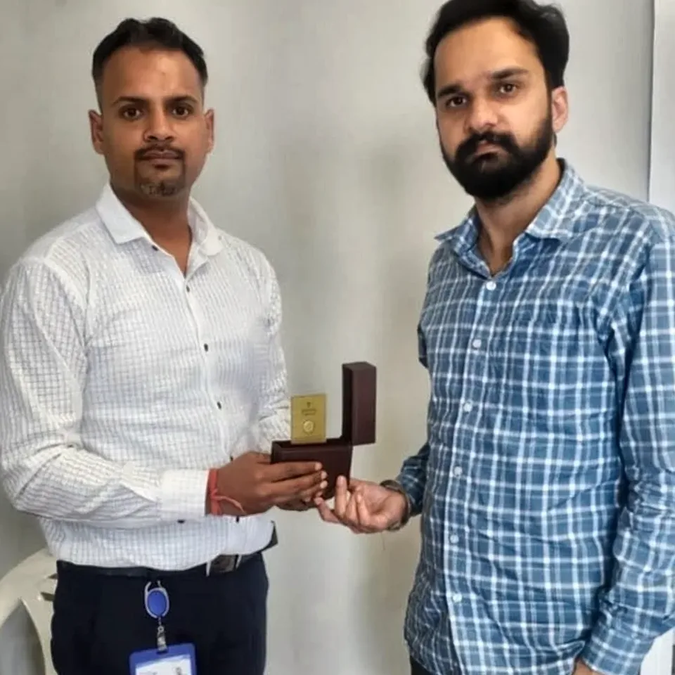 A ProperPaisa advisor handing a Tanishq gold coin to a customer after their loan was disbursed