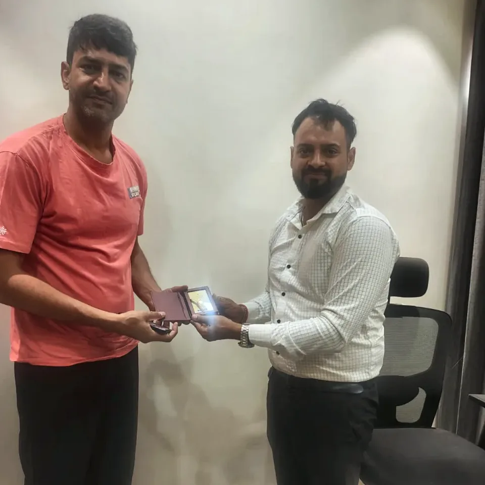 A ProperPaisa advisor handing a Tanishq gold coin to a customer after their loan was disbursed