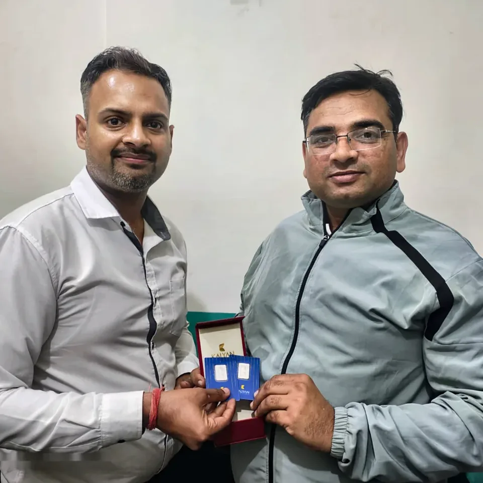 A ProperPaisa advisor handing a Kalyan Jewellers 999 silver coin to a customer after their loan was disbursed